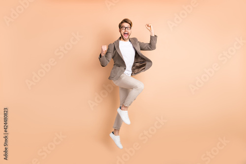 Full body profile side photo of attractive happy crazy man jump up air celebrate win isolated on beige color background