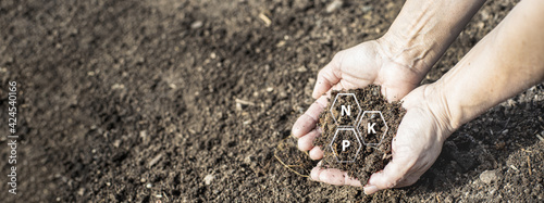 Fresh compost soil in two hands with symbols of the most important nutrients.