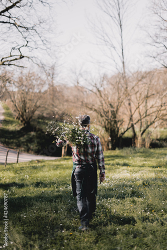Gardener walking in a field with a bunch of flowering branches