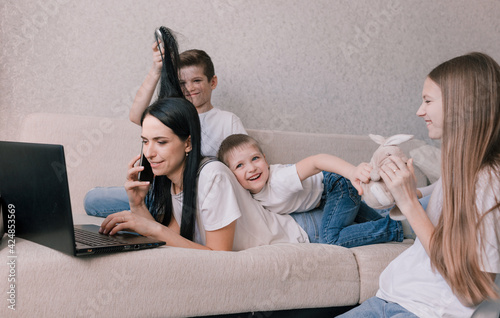 active children indulge, interfere and distract their mother while working at home on a laptop. working during a pandemic. freelancer remote work