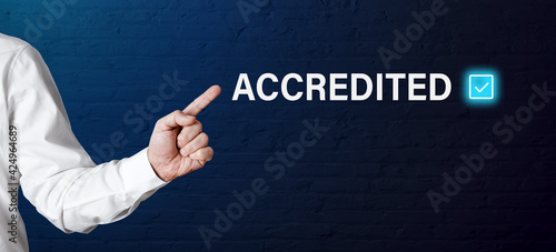 Businessman hand points to the word accredited