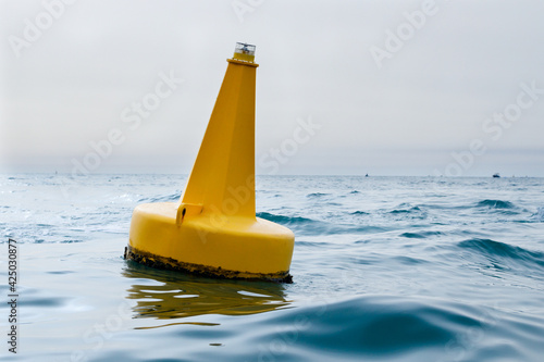 Yellow navigational sea buoy in the waves in the marina near Dubai