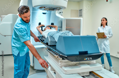 A young woman is undergoing radiation therapy for cancer under the supervision of doctors in a modern cancer hospital. Cancer therapy, advanced medical linear accelerator.