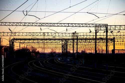 Poles with electric wires near the railway at sunset. Background