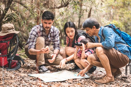 A group of young Asians are planning and looking at maps for camping in the forest.Asian and caucasian are backpackers.Tourism, adventure and summer vacation concept