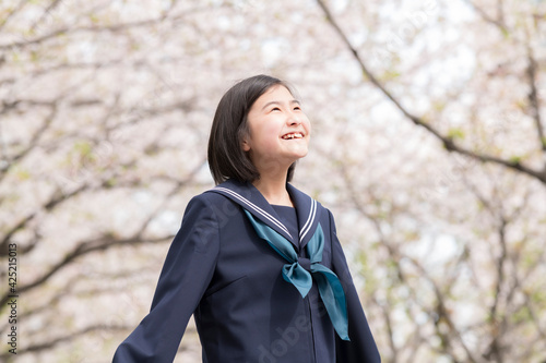 満開の桜並木と新入学の中学生