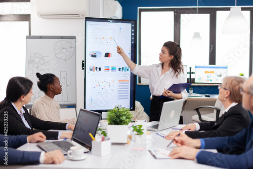 Executive director woman briefing collegues, explaning company strategy during brainstorming. Multiethnical businesspeople working in professional startup financial office during conference meeting