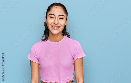 Hispanic teenager girl with dental braces wearing casual clothes with a happy and cool smile on face. lucky person.