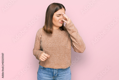 Young beautiful woman wearing casual clothes smelling something stinky and disgusting, intolerable smell, holding breath with fingers on nose. bad smell