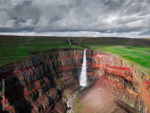 Aerial drone view of Hengifoss waterfall landscape in Iceland. Red layers of clay between basaltic layers. Icelandic nature from above