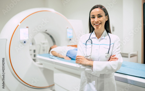 Confident female doctor oncology in magnetic resonance imaging or computed tomography room of a modern hospital.