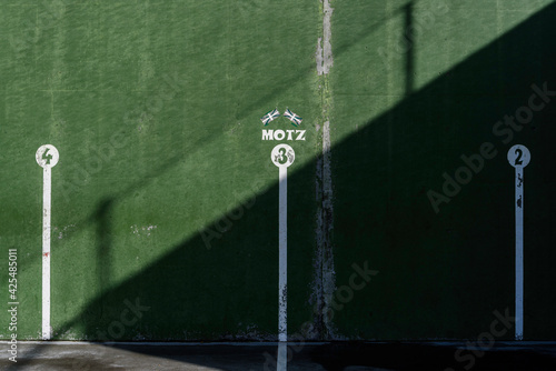 fronton wall in the Basque ball sport, in which the game marks are painted with the numbers 3 in the middle and 2 and 4 on both sides. Above the number 3 there are two Basque flags and the word, Motz,