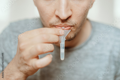 Lateral-Flow-Test covid rapid home-use test kit for saliva - step 1 - spit with mouth through funnel in plastic tube to collect sample - No more swabs in the throat or nose: just spit in a tube!