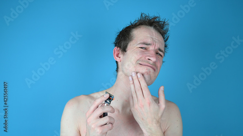 Portrait of a sad disgruntled man on blue background. Skin irritation after shaving on mans skin