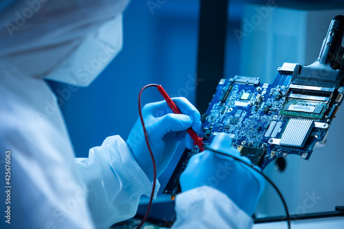 Microelectronics engineer works in a modern scientific laboratory on computing systems and microprocessors. Electronic factory worker is testing the motherboard and coding the firmware.