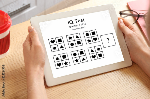 Woman using tablet for taking IQ test indoors, closeup