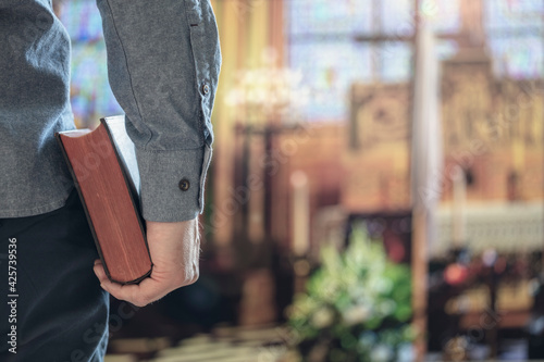 Man holding holy bible in church with alter in background