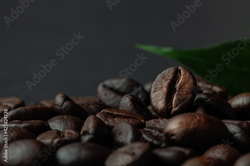 Roasted coffee beans with leaf on the old dark wooden background for wallpaper or decor. Shallow depth of field. Selected focuse. Toned