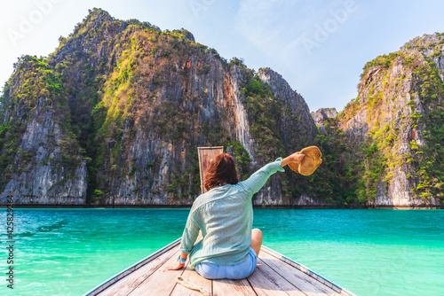 Back view of happy woman traveler relaxing on boat at Andaman sea, Phi Phi island, Krabi province Thailand Asia, Summer holiday outdoors vacation trip.
