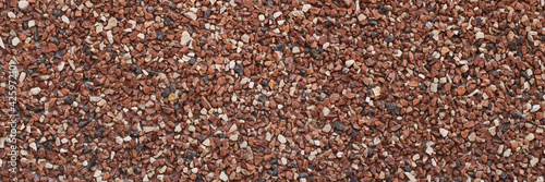 Texture of small stones, rocky abstract background, grainy surface, gravel pattern, red pebbles. Decorative design, brown colored. Grunge wall backdrop.