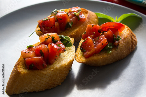 Italian bruschetta with roasted tomatoes, basil and garlic. Top view photo of savory toast. Healthy eating concept. 