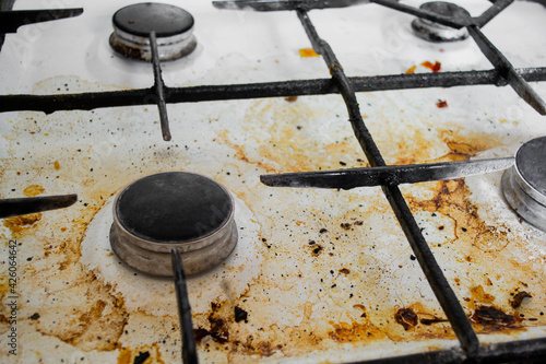 Top view of a very dirty white gas stove with yellow streaks and greasy spots