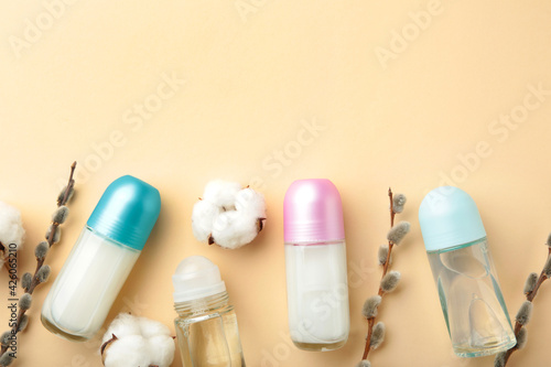 White deodorants with willow twigs on beige background.