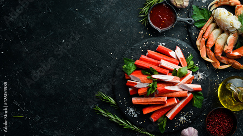 Crab sticks from a crab on a black stone plate. Rustic style. Seafood delicacies.