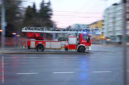 Samochód straży pożarnej z drabiną alarmowo na sygnale. 