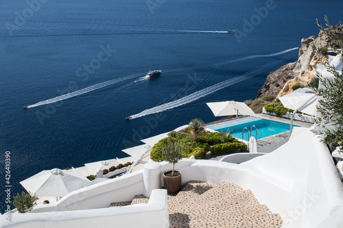 Perfect view of Santorini: swimming pool in luxury hotel, yachts and Mediterranean sea.