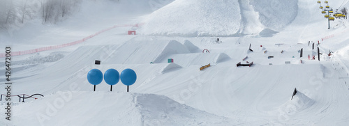 Panoramic view of snowpark with figures for freestyle jumping and jibbing in ski resort