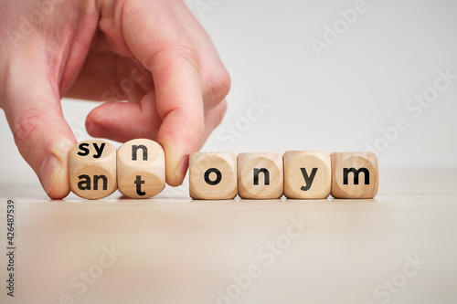 Hand flips wooden cubes with the inscription antonym and synonym