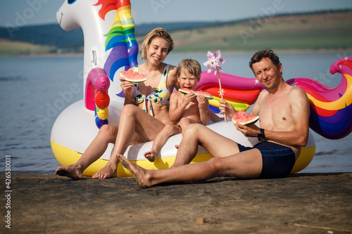 Happy family playing at the beach. Unicorn Colorful Inflatable Floating