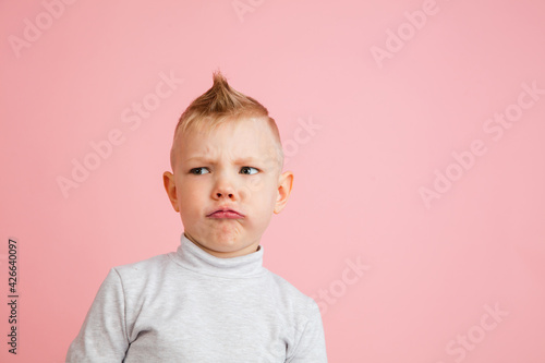 Happy boy isolated on pink studio background. Looks happy, cheerful, sincere. Copyspace. Childhood, education, emotions concept