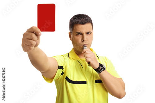 Serious football referee blowing a whistle and showing a red card