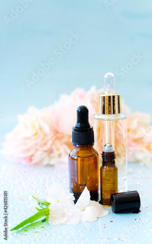 Cosmetic bottles on a blue background. Fresh flowers lie nearby. Natural cosmetic