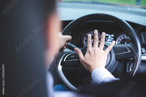 Close up image of inside the car of the hand pressing the horn on the steering wheel.Safe driving concept