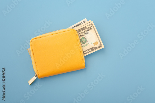 Money in yellow wallet on blue background