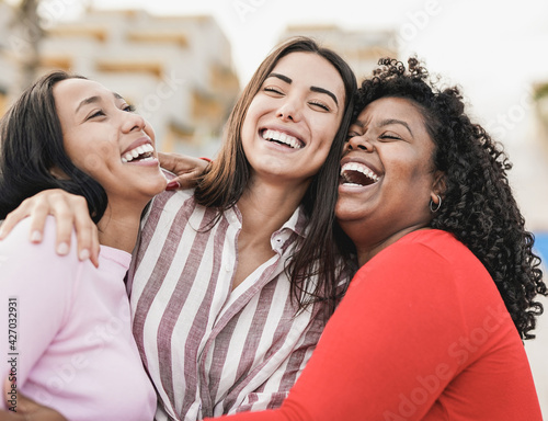 Happy latin women laughing and hugging each other outdoor in the city - Millennial girls and friendship concept
