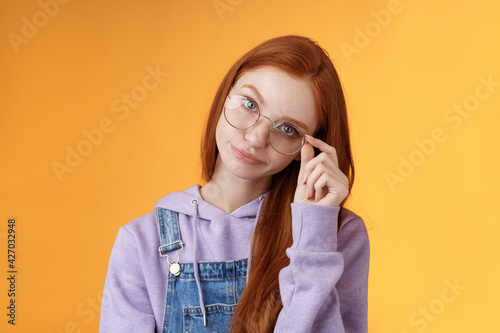 Annoyed bossy unimpressed bothered young redhead female coworker smirking tilting head irritated touch glasses look ignorant cringing stupid uninteresting doubtful story not buy any excuses