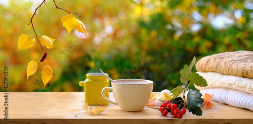 wooden table in the garden, tea, coffee in a mug, a candle is burning in a candlestick, long panorama, the concept of an outdoor tea party, good weather, a cozy autumn mood