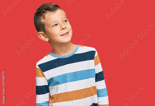 Adorable caucasian kid wearing casual clothes looking away to side with smile on face, natural expression. laughing confident.