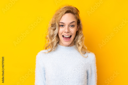 Young blonde woman isolated on yellow background with surprise facial expression