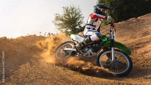 Young man practice riding dirt bike.Splashing sand