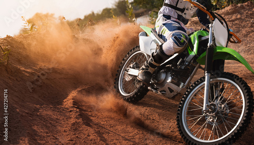 Young man practice riding dirt bike.Splashing sand