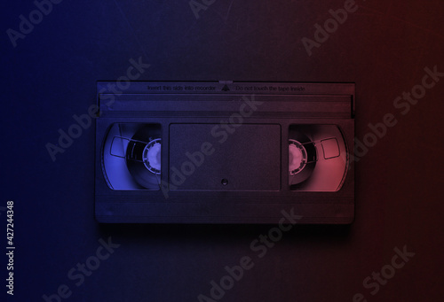 Video cassette in neon light. Retro storage media, videotape. 80s