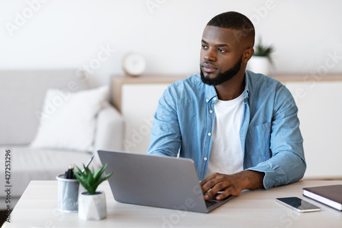 Portrait Of Pensive Black Male Freelancer Sitting At Desk In Home Office