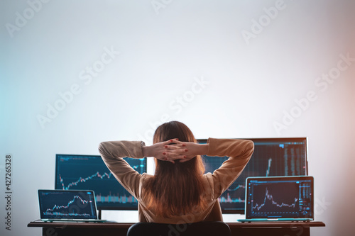 back view of female crypto trader resting and looking at monitor stock exchange