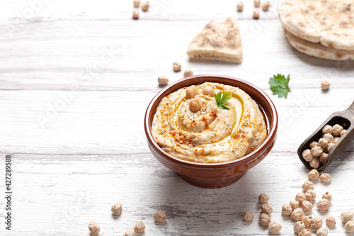 Bowl of homemade hummus on light background with copyspace.