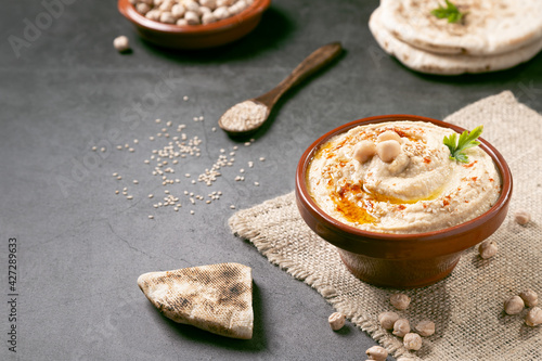 Bowl of homemade hummus on dark background with copyspace.